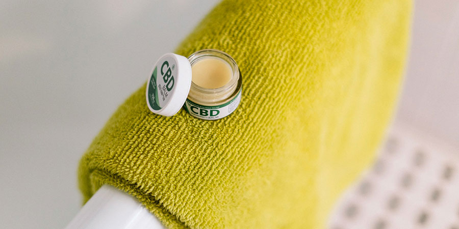 a small round container of CBD balm on top of a yellow towel